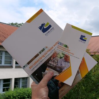 Eine Hand zeigt Broschüren zum Thema Senioren aus dem Landkreis Coburg 