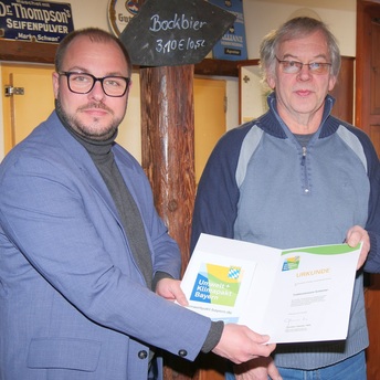 Sebastian Straubel überreicht an Oskar Dölliger eine Urkunde mit dem Logo des bayerischen Umwelt- und Klimapakts.