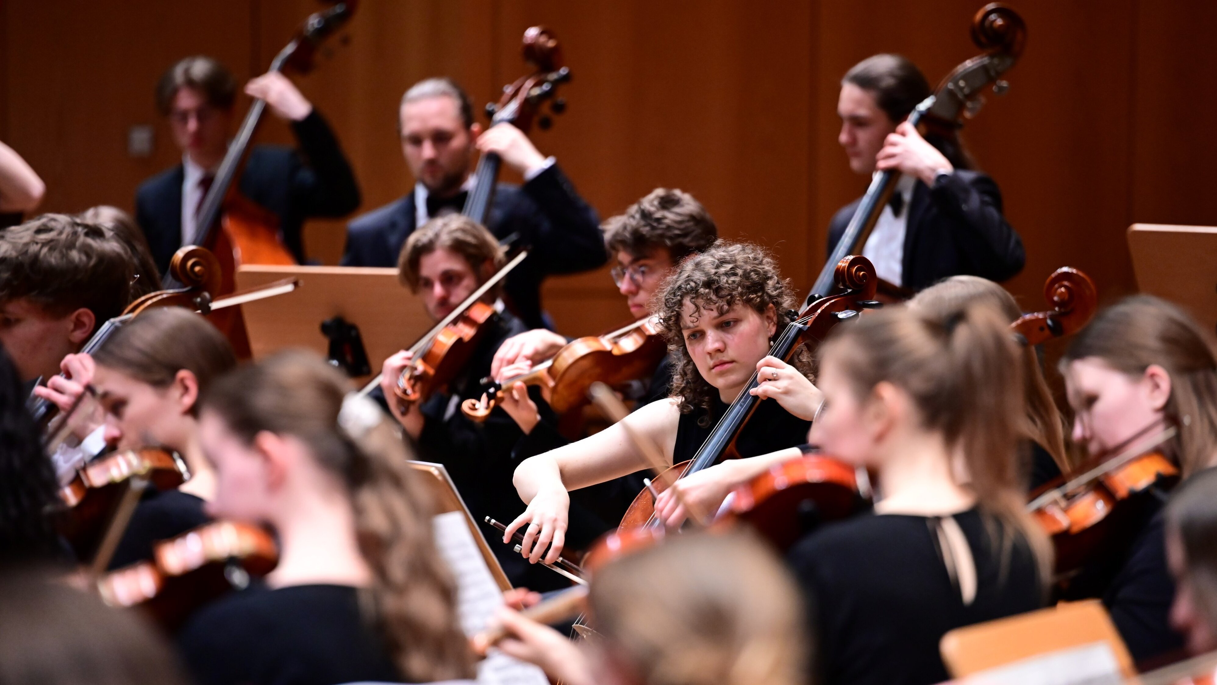 Junge Orchestermusiker mit klassischen Instrumenten bei einer Orchesterprobe.