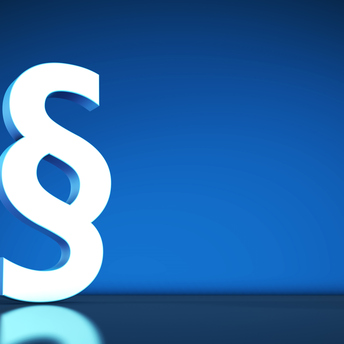 Ein weißes Paragraphenzeichen steht vor einem blauen Hintergrund. 