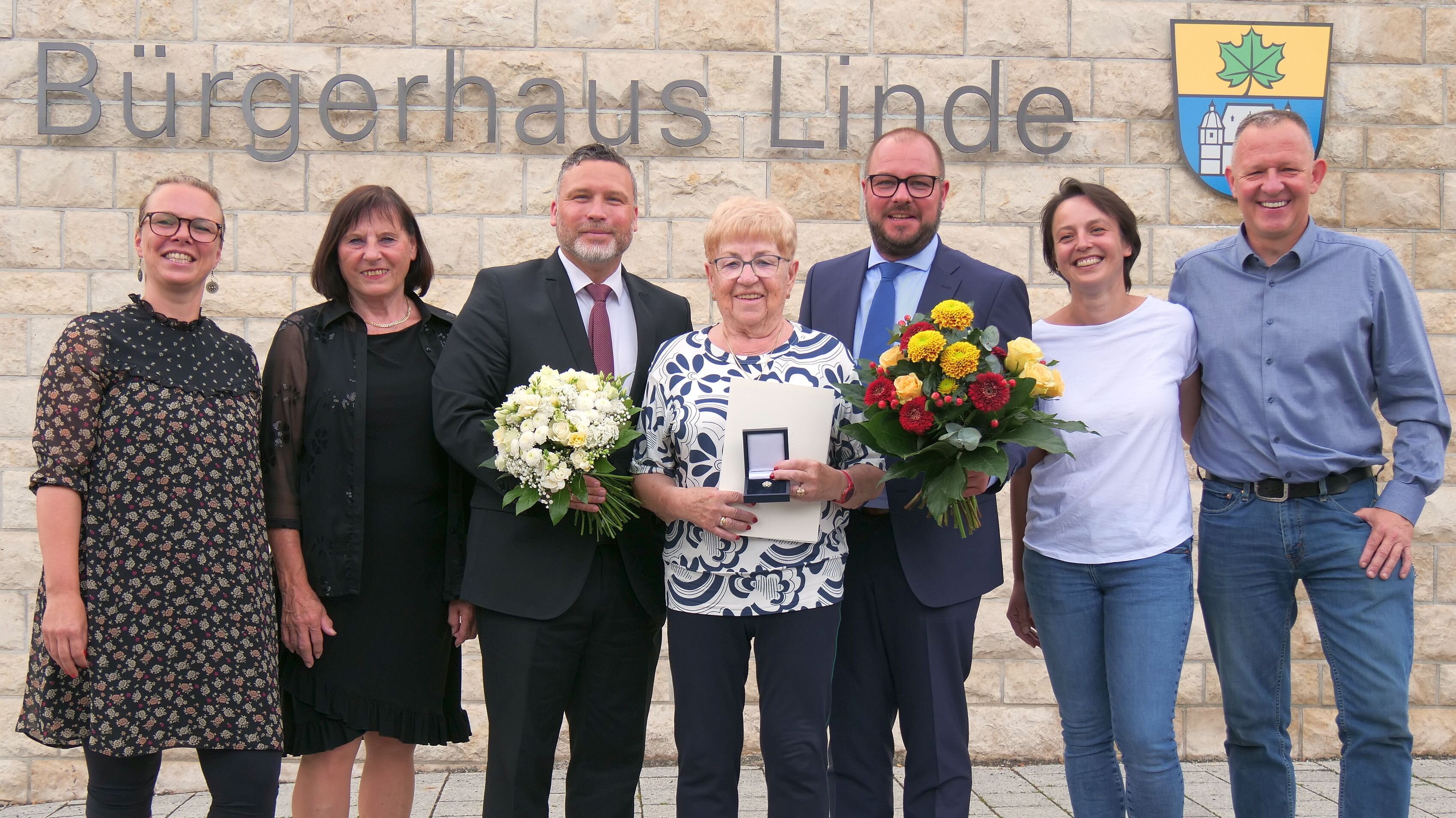 Gruppenbild mit sieben Personen. In der Mitte steht Gudrun Zwilling die das Ehrenzeichen des Bayerischen Ministerpräsidenten in der Hand hält. An der Wand im Hintergrund ist der Schriftzug Bürgerhaus Linde zu lesen.