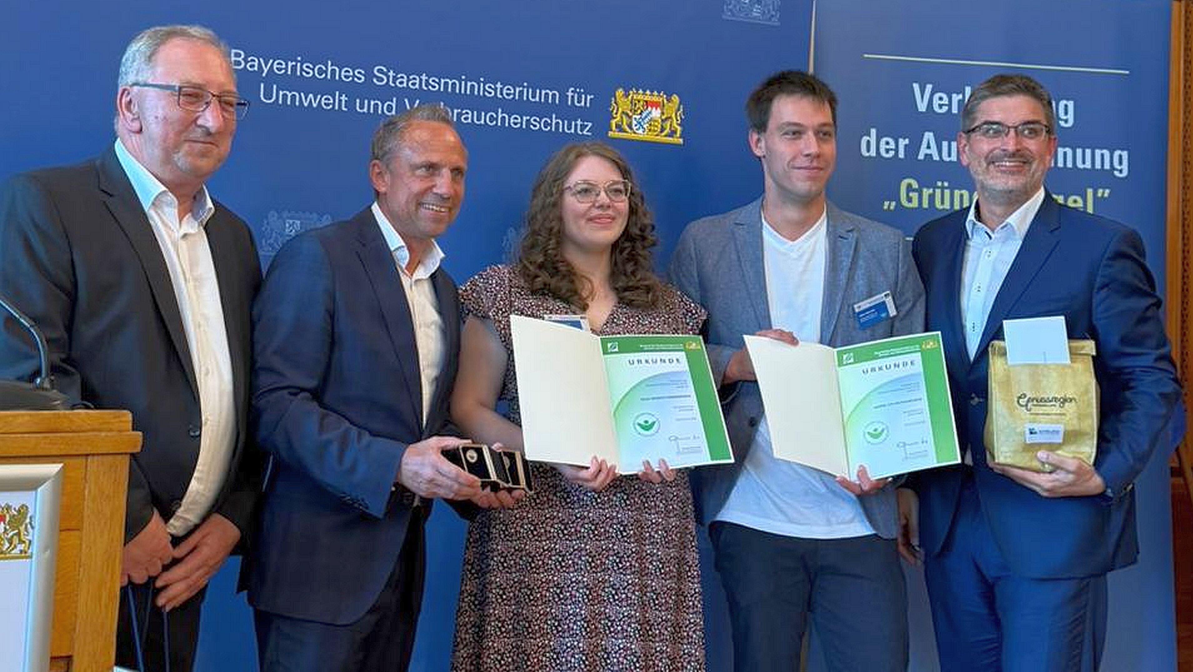 Serena Eisenwiener und Julian Hauschild halten die Urkunden für den Grünen Engel in der Hand. Neben ihnen stehen Gerd Mücke, Umweltminister Thorsten Glauber und Christian Gunsenheimer.