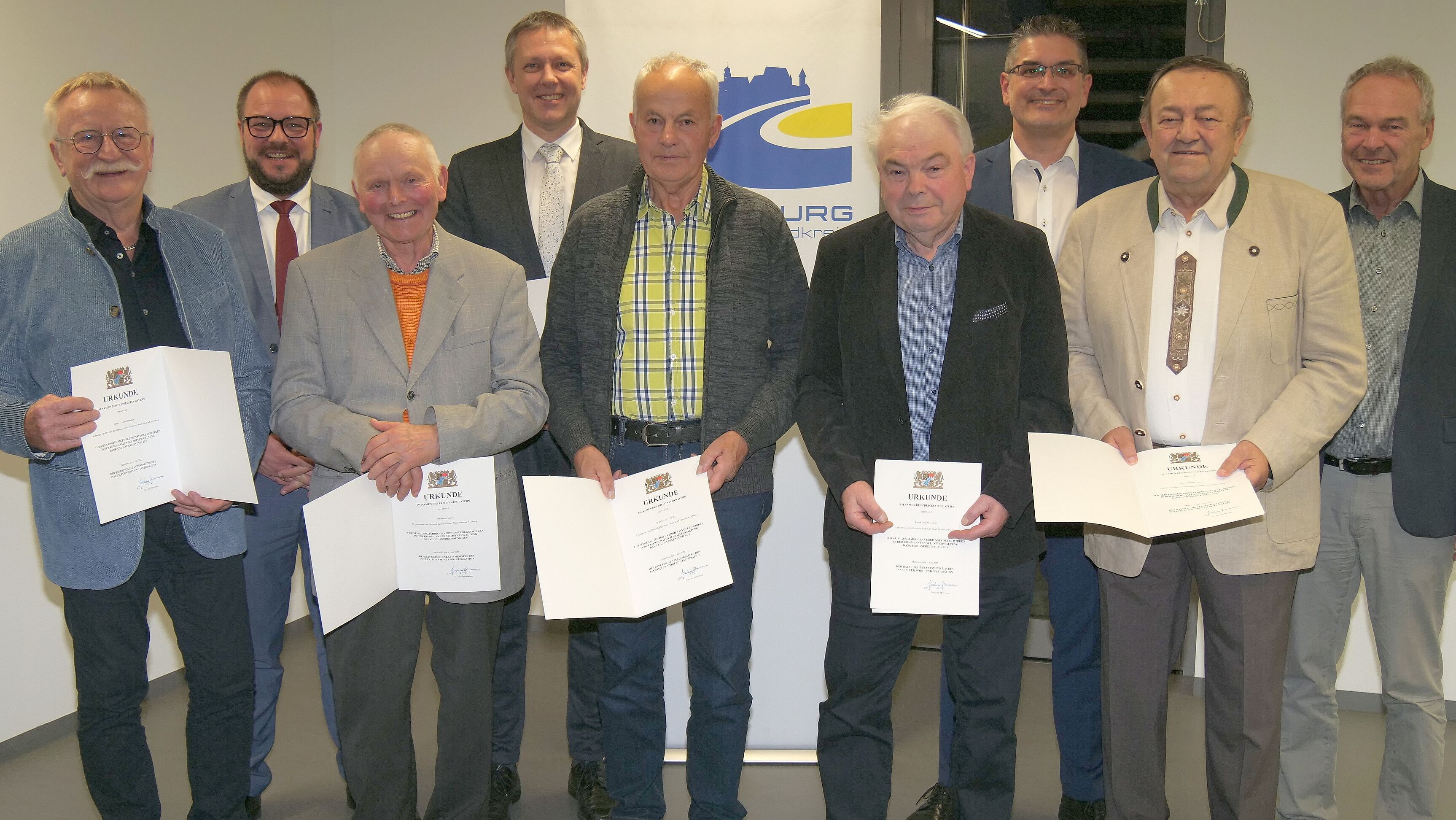 Die Empfänger der Kommalen Dankurkunde stehen nebeneinander in einer Reihe und halten ihre Urkunden in der Hand.