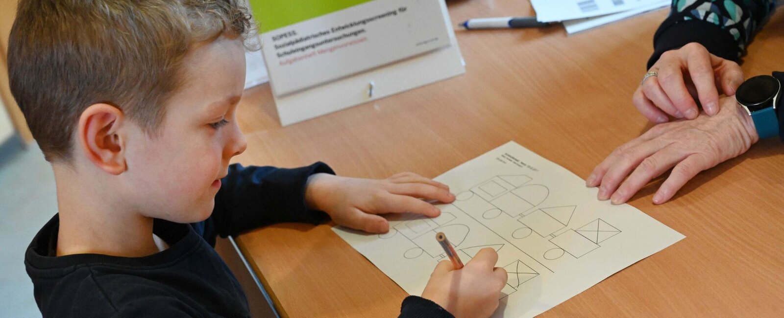 Ein Schulkind füllt einen Test unter Anleitung aus. 