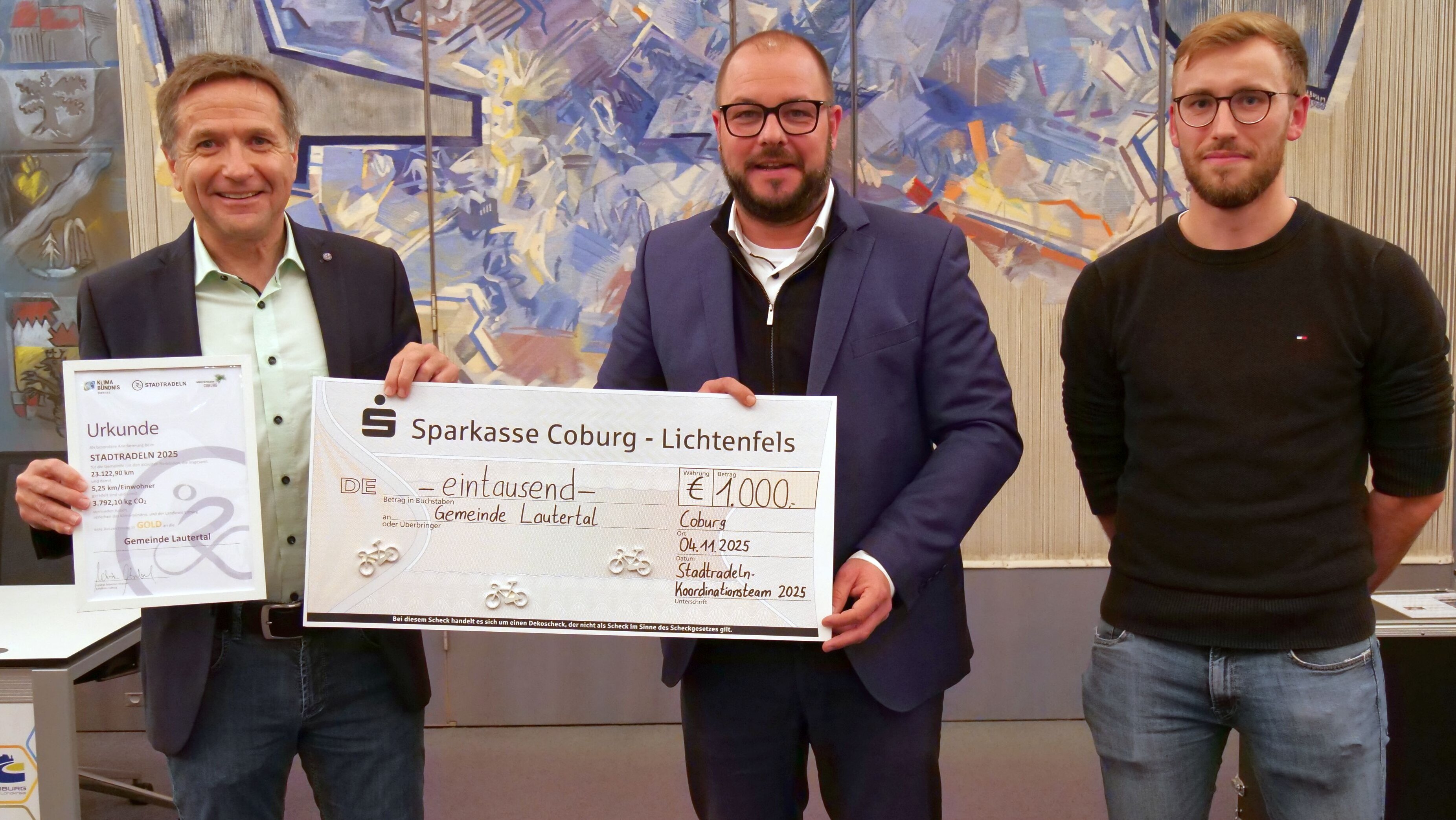 Bürgermeister Karl Kolb aus Lautertal und Sebastian Straubel halten den Siegerscheck für die beste Gemeinde, rechts steht Dominik Wank vom Landratsamt Coburg.