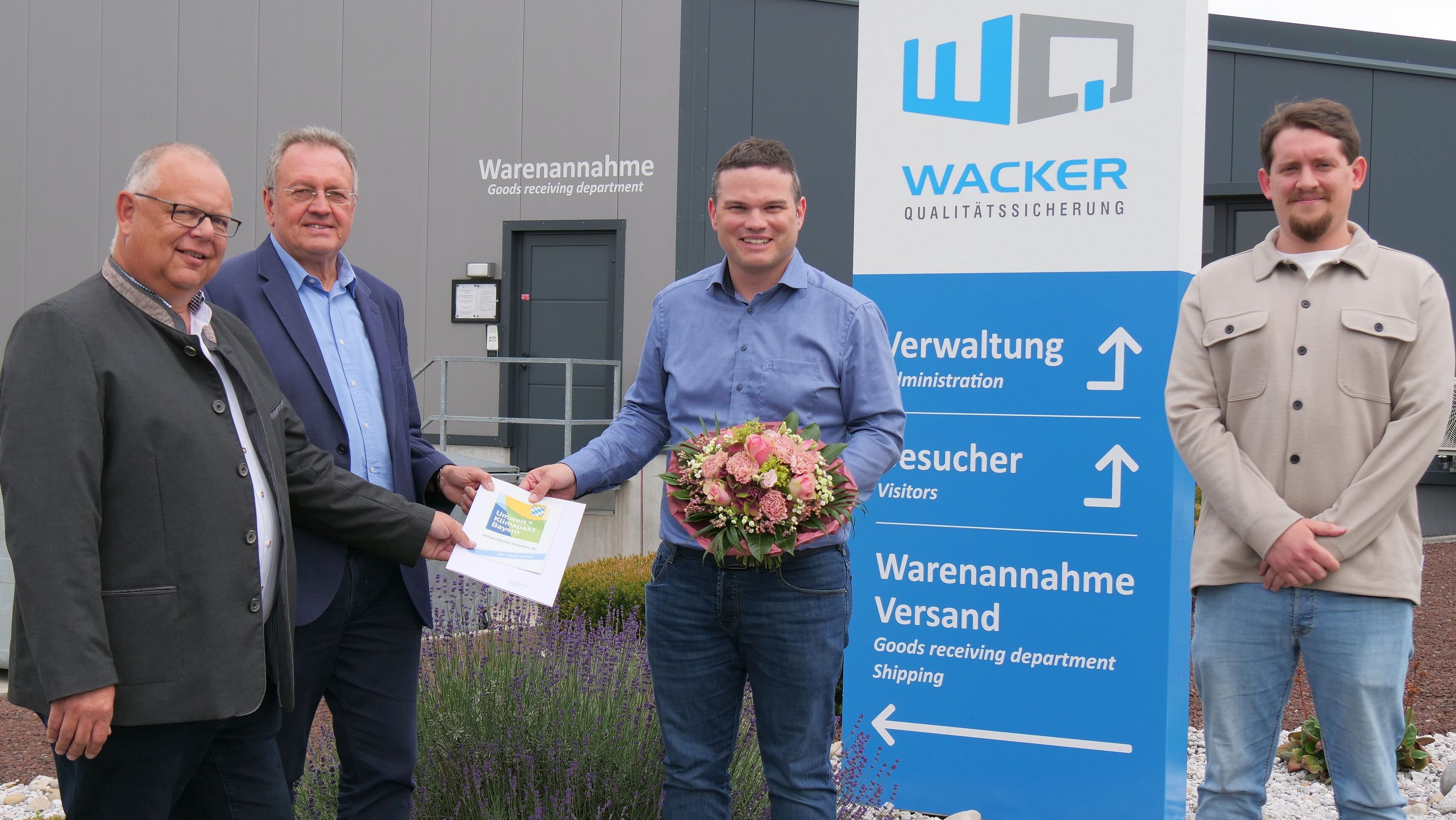 Martin Stingl, Udo Siegel, Andreas Wacker und Andreas Schubert stehen mit der Urkunde für die Teilnahme am Klima- und Umweltpakt vor dem Firmengegäude der Wacker Qualitätssicherung GmbH 