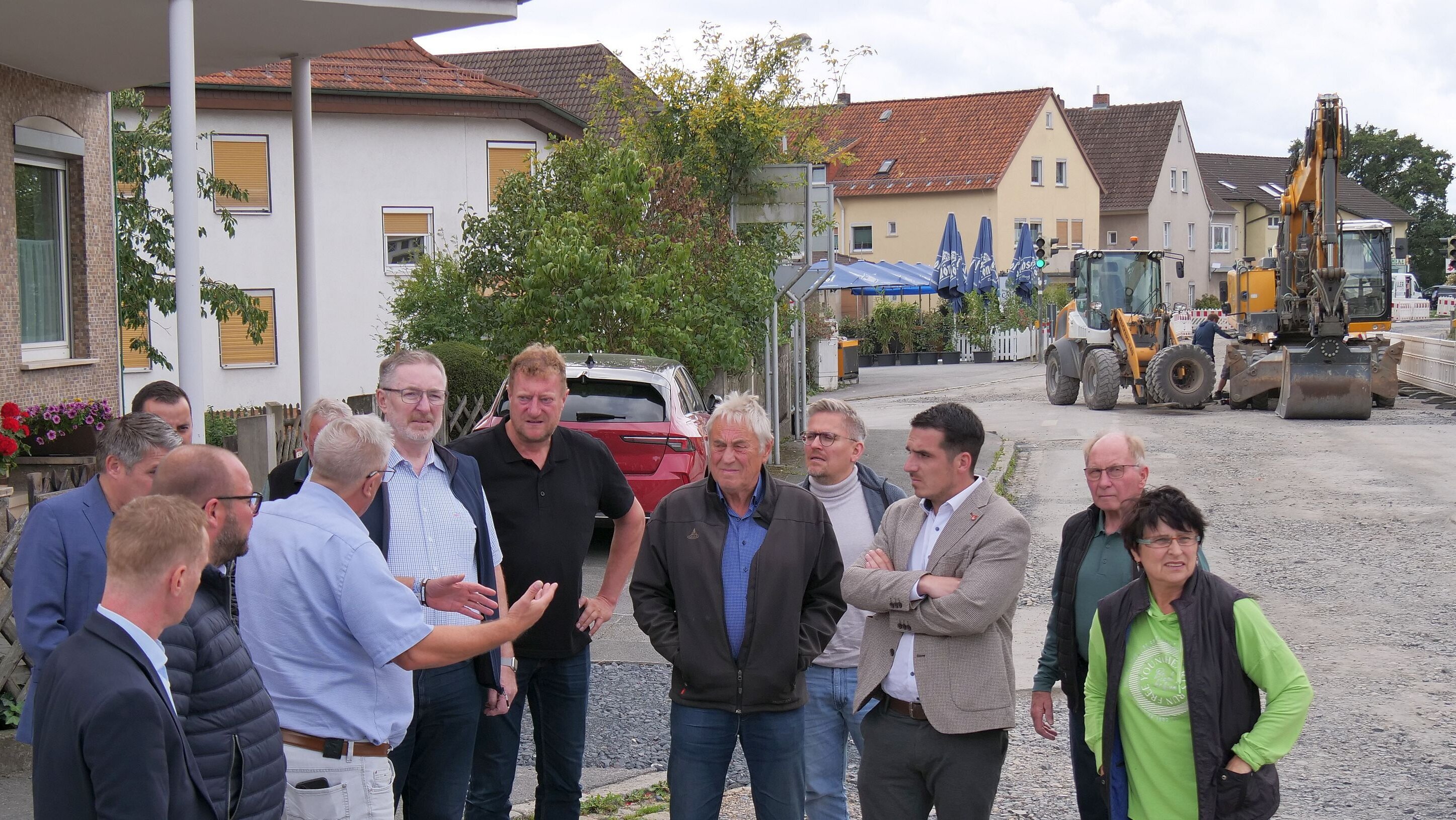Die Mitglieder des Bauausschuss stehen auf der Baustelle der Ortsdurchfahrt in Dörfles-Esbach. Im Hintergrund sind die aufgerissene Straßen sowie mehrere Baufahrzeuge zu sehen.