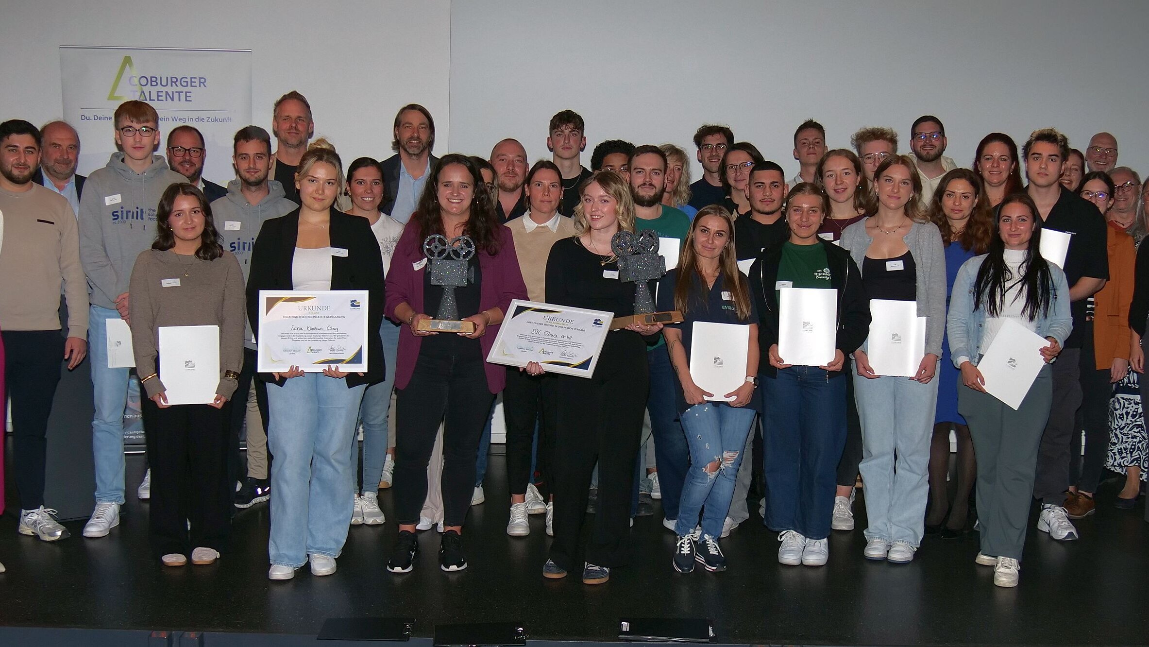 And the Winner is… Die Siegerehrung beim Wettbewerb für Azubi-Videos des Landkreisses: (von links) Natalia Spieß, Yana Kovalenko, Mathias Axmann, Jenny Staroske, Franzi Bauersachs, Sina Weiß und Rebecca Stephan. Vorne stehen die Gewinner mit Urkunden und den Siegestrophäen in der Hand.