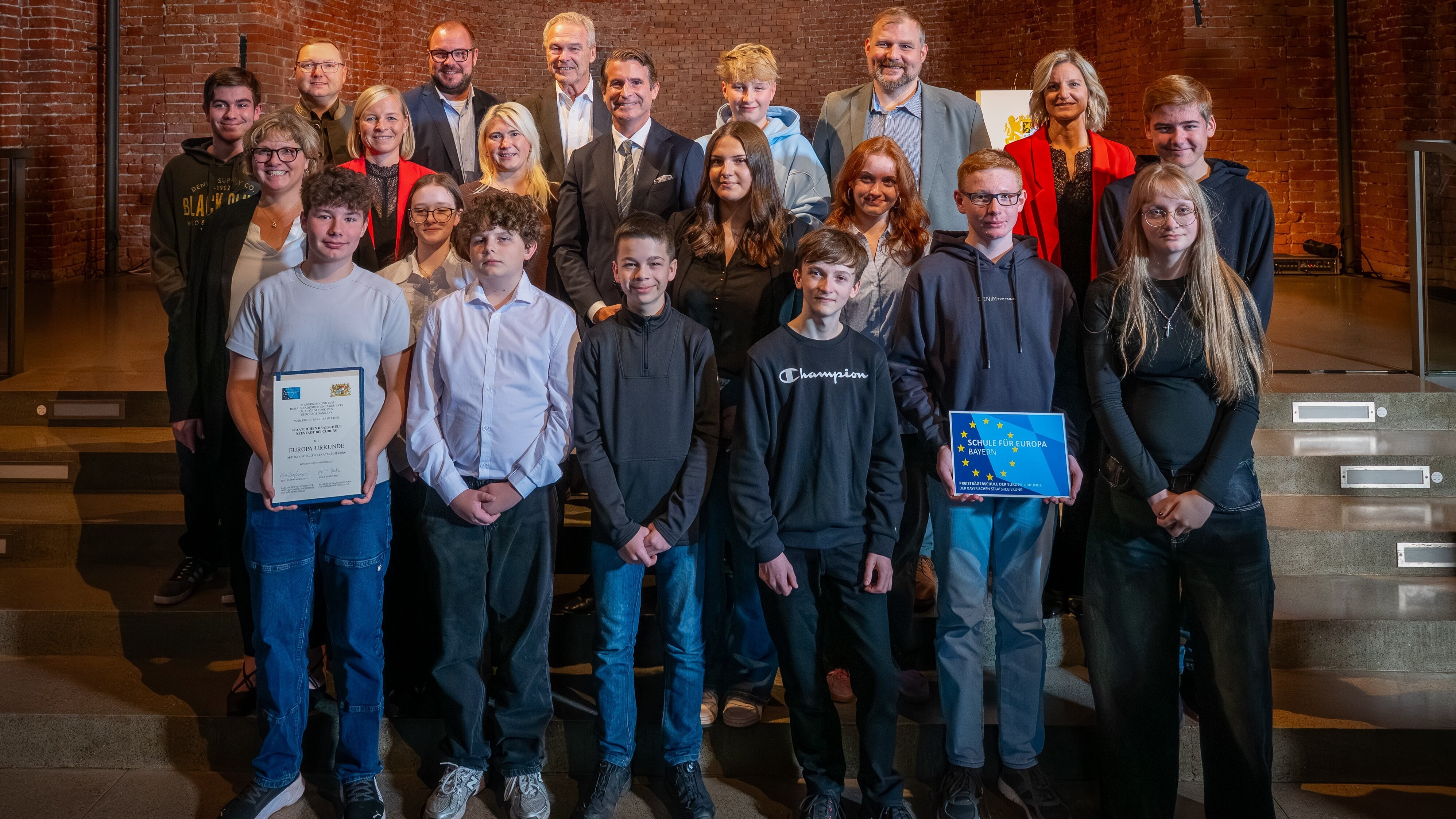 Eine Gruppe von Schülern. Zwei von Ihnen halten Urkunden und das Europa-Logo in der Hand.
