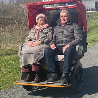 Ein älteres Paar sitzt in einer Rikscha 