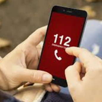 Hände halten ein Handy, auf dem vor rotem Hintergrund die Notrufnummer 112 aufleuchtet 