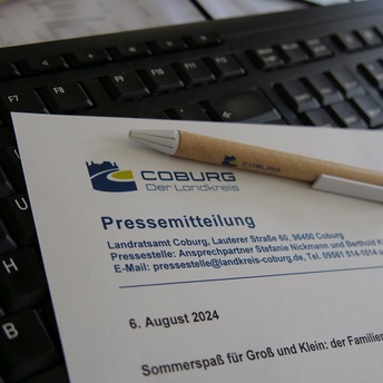 Ein Papier mit der Aufschrift "Pressemitteilung" liegt auf einer Tastatur. 