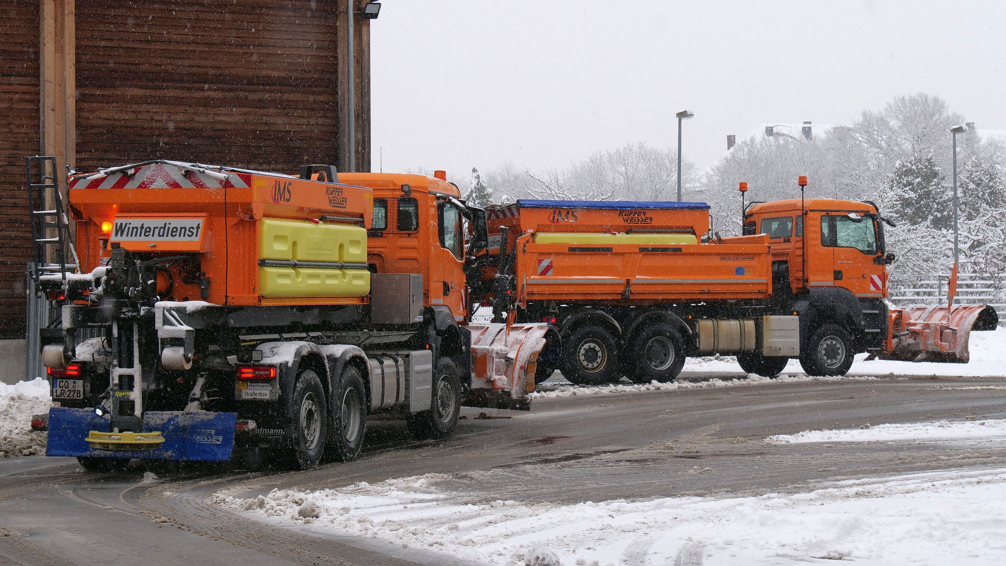 Zwei orangefarbene Schneeräumefahrzeug stehen auf dem Home der Kreisstraßenmeisterei.