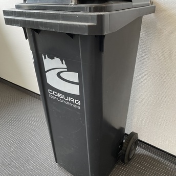 Eine graue Tonne mit dem Symbol des Landkreises Coburg steht vor einer Wand. 