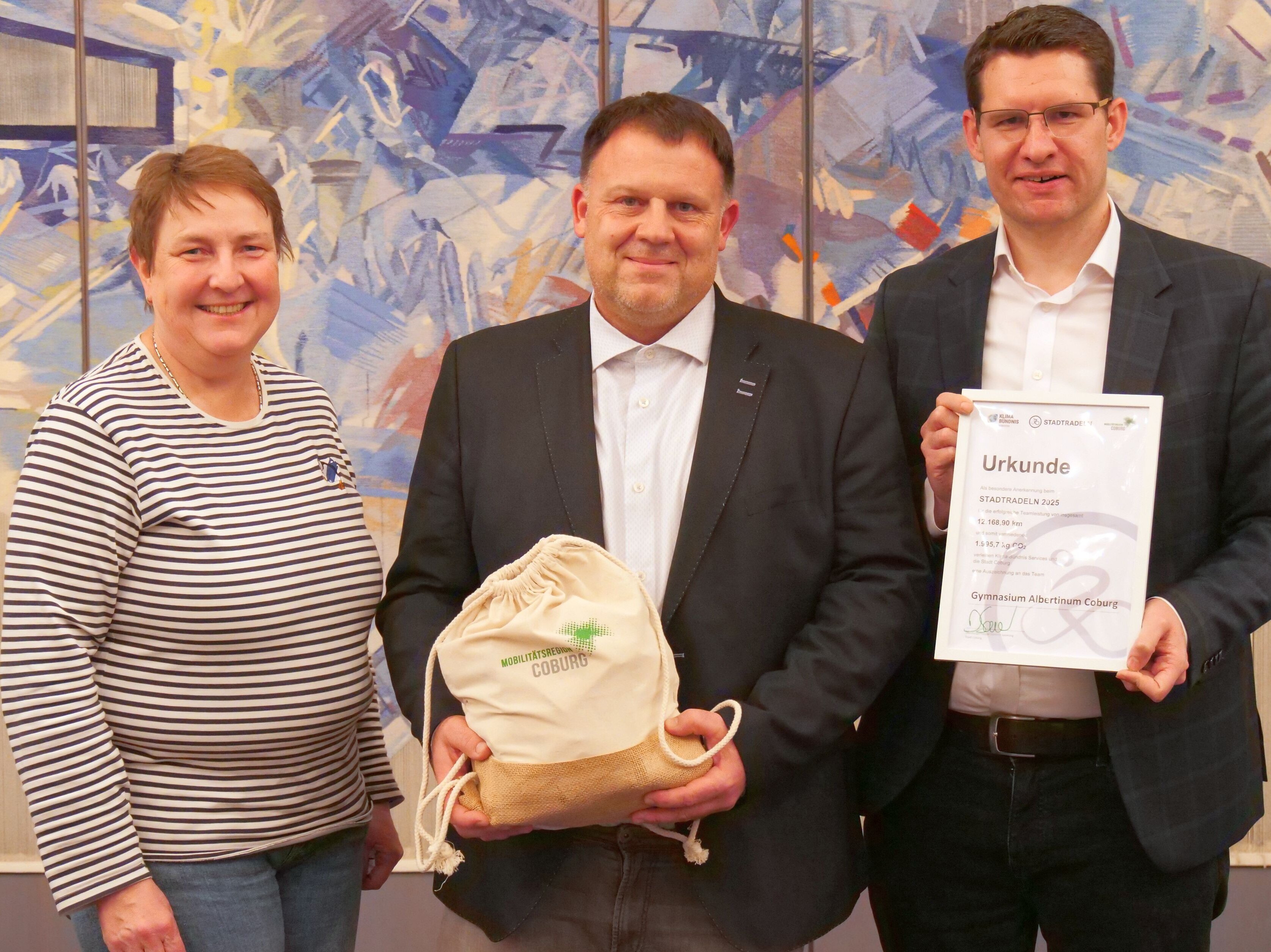 Michael Dehler vom Albertinum Coburg mit dem Sachpreis für die beste Schule in der Hand, neben ihm stehen Marita Nehring und Dominik Sauerteig.