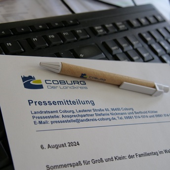 Ein Blatt mit der Aufschrift "Pressemitteilung" liegt mit einem Stift auf einem Schreibtisch 