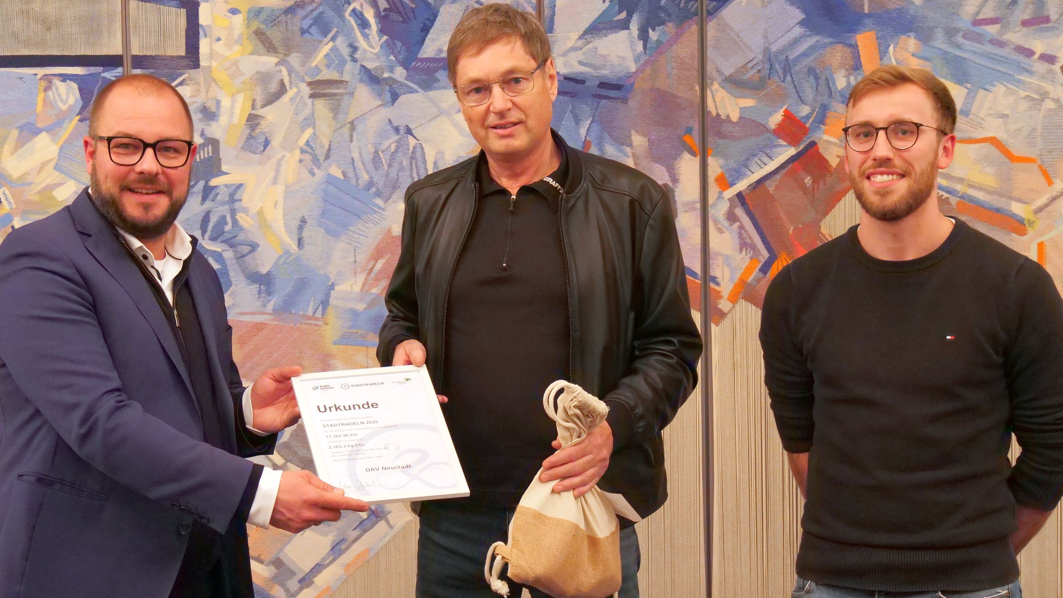 Klaus Frenzel nimmt aus der Hand von Sebastian Straubel die Siegerurkunde für den erfolgreichen Verein aus dem Landkreis Coburg beim Stadtradeln entgegen. Rechts steht Dominik Wank vom Landratsamt Coburg.